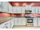 Bright kitchen featuring stainless steel appliances, granite countertops, and light gray cabinetry at 18951 Grand Club Dr, Hudson, FL 34667