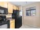 Kitchen featuring black appliances, tile floors, light wood cabinetry, and natural lighting at 2073 Skimmer W Ct # 211, Clearwater, FL 33762