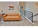Contemporary loft space with a brown sofa, black railing, wood-look floors, and wall decor for modern living at 2985 W Knights Ave # 2985, Tampa, FL 33611