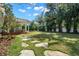 Large backyard with a covered outdoor living space, a pool, lush greenery, and stone walkways at 3412 W Mckay Ave, Tampa, FL 33609