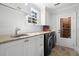 Well-lit laundry room featuring black washer/dryer and granite countertops at 3412 W Mckay Ave, Tampa, FL 33609