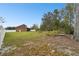 Large backyard showing a home with an expansive grassy lawn, trees, and a white fence at 3613 Pendleton Way, Land O Lakes, FL 34639