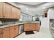 Kitchen featuring granite counters, wood cabinetry, stainless steel dishwasher, and an open design to the living area at 3613 Pendleton Way, Land O Lakes, FL 34639