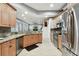 Open kitchen featuring stainless steel appliances, wood cabinets, and granite countertops with views to the Gathering room at 3613 Pendleton Way, Land O Lakes, FL 34639