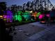 Inviting backyard featuring a fire pit, palm trees illuminated by colorful lights at twilight at 3655 Candia Ave, North Port, FL 34286