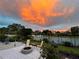 Cozy backyard featuring a fire pit, outdoor seating, lush lawn, and palm trees against a vibrant sunset backdrop at 3655 Candia Ave, North Port, FL 34286