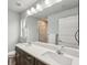 Bathroom featuring double sinks, a spacious mirror, and a beautifully tiled shower at 3655 Candia Ave, North Port, FL 34286