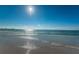 Waves gently rolling onto the beach under a sunny, cloudless sky with a pier in the distance at 642 Blue Taverna Ln, Clearwater, FL 33756