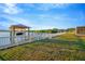 Waterfront view of the manicured lawn, white fencing, and dock with a covered boat lift at 8841 W Millpoint Rd, Riverview, FL 33578