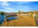 Waterfront home featuring a private wooden dock with a boat lift under a blue sky at 8841 W Millpoint Rd, Riverview, FL 33578