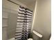 Bathroom featuring a shower-tub combo with a striped shower curtain, maximizing space in a neutral color palette at 11517 Timber Grove Ln, Brooksville, FL 34613