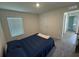 Cozy bedroom with neutral carpet, a comfortable bed, a window with blinds, and a door to the hallway at 11517 Timber Grove Ln, Brooksville, FL 34613