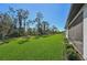 Lush green lawn alongside the home with a view of the tree line at 1848 Sunset Preserve Way, Port Charlotte, FL 33953