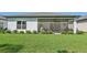 A plush green backyard with a view of a screened-in patio and the back of the house at 1848 Sunset Preserve Way, Port Charlotte, FL 33953