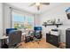 Home office featuring two desks, multiple monitors, and a large window for natural light at 1848 Sunset Preserve Way, Port Charlotte, FL 33953
