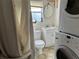 Compact bathroom with a toilet, sink, shower, and convenient laundry appliances at 2980 64Th N Ave, St Petersburg, FL 33702