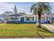 Charming single-story home with a well-manicured lawn, palm trees, and a light blue door at 4208 Woodfield Ave, Holiday, FL 34691