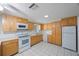 Traditional kitchen boasts natural wood cabinets, white appliances, and bright white tile flooring at 5317 Tammy Ln, Holiday, FL 34690