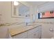 Bathroom features a vanity with a granite countertop, white cabinets, and a decorative mirror at 6800 Sunset Way # 1003, St Pete Beach, FL 33706