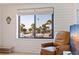 Living room featuring tiled floors, comfortable seating, and a large window with a view of palm trees and the beach at 6800 Sunset Way # 1003, St Pete Beach, FL 33706
