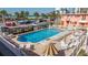 Community pool surrounded by lounge chairs, tables, and umbrellas at 6800 Sunset Way # 1003, St Pete Beach, FL 33706