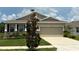 Charming one-story home featuring neutral color, two-car garage, manicured lawn and beautiful blue skies at 8438 Wheat Stone Dr, Zephyrhills, FL 33540