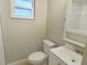 A bright, white bathroom with a standard toilet, vanity, and tile shower featuring a window for natural light at 9062 Sunrise Dr, Largo, FL 33773