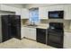 Well-lit kitchen featuring white cabinets, black appliances, light countertops, and tile flooring at 9062 Sunrise Dr, Largo, FL 33773