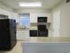Bright kitchen with white cabinets, tile flooring, black appliances, light countertops, and a center island at 9062 Sunrise Dr, Largo, FL 33773