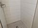 Close up of a tiled shower stall with white subway tile and a black and white patterned tile floor at 9062 Sunrise Dr, Largo, FL 33773