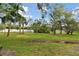 Green backyard with a lush lawn, mature trees, and a puddle of water at 9770 Indian Key Trl # 102, Seminole, FL 33776
