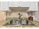 Close-up of the kitchen sink featuring a stainless steel sink and a tile backsplash at 9770 Indian Key Trl # 102, Seminole, FL 33776