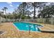 Community pool surrounded by mature trees, white fence, and brick pavers, creating a relaxing atmosphere at 9770 Indian Key Trl # 102, Seminole, FL 33776