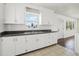 Well-lit kitchen featuring white cabinets, tile flooring, an undermount sink, and a view of the living area at 106 W North Branch Rd, Ruskin, FL 33570