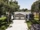 Well-lit single-story home with attached two-car garage, long driveway, and mature trees in the front yard at 14334 Channel Dr, Largo, FL 33774