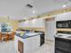 Eat-in kitchen featuring white cabinets, blue countertops, and black appliances at 1434 Glengarry Dr, Palm Harbor, FL 34684