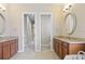 Elegant bathroom featuring double vanities with granite countertops, framed mirrors and tile flooring at 15708 Oakleaf Run Dr, Lithia, FL 33547