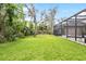 A spacious backyard with green lawn and mature trees with a screened-in pool area at 15912 Ternglade Dr, Lithia, FL 33547