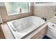 Close up of tiled bathtub with jacuzzi jets by window in primary bathroom at 15912 Ternglade Dr, Lithia, FL 33547