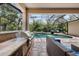 Outdoor kitchen and covered lounge area near a screened-in pool and spa at 15912 Ternglade Dr, Lithia, FL 33547