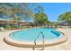 Large Kidney shaped community pool surrounded by lounge seating and mature trees at 1844 Bough Ave # C, Clearwater, FL 33760