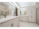 Bright bathroom featuring double vanity sinks, large mirrors, walk-in shower, and storage cabinets at 18806 Autumn Lake Blvd, Hudson, FL 34667