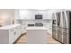 Modern kitchen with stainless steel appliances, quartz countertops, white cabinets, and light wood floors at 18806 Autumn Lake Blvd, Hudson, FL 34667