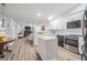 Open-concept kitchen with white cabinets, stainless appliances, and views of living area and fireplace at 18806 Autumn Lake Blvd, Hudson, FL 34667