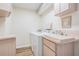 Functional laundry room featuring a sink, washer, and dryer with light wood cabinets for all your cleaning needs at 18806 Autumn Lake Blvd, Hudson, FL 34667