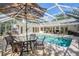A screened-in pool with an umbrella table and chairs provides a backyard oasis at 18806 Autumn Lake Blvd, Hudson, FL 34667