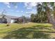 Expansive backyard boasts lush lawn, screened-in pool, complemented by mature palm trees enhancing the serene outdoor space at 20191 Rutherford Ave, Port Charlotte, FL 33952