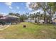 Spacious backyard featuring green grass, a fire pit, screened-in pool, and mature trees providing ample shade at 20191 Rutherford Ave, Port Charlotte, FL 33952
