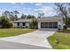Well-manicured lawn leading to a light gray house with a black two car garage door and driveway at 20191 Rutherford Ave, Port Charlotte, FL 33952