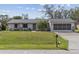 Inviting front exterior features a manicured lawn, mature palm, and a covered two-car garage at 20191 Rutherford Ave, Port Charlotte, FL 33952